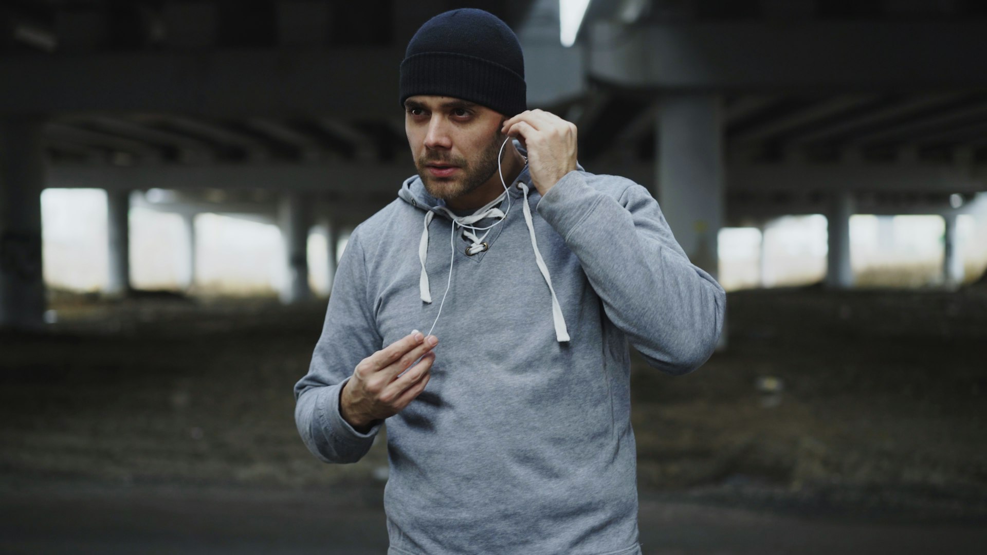 Man in beanie and hoodie putting in earbuds